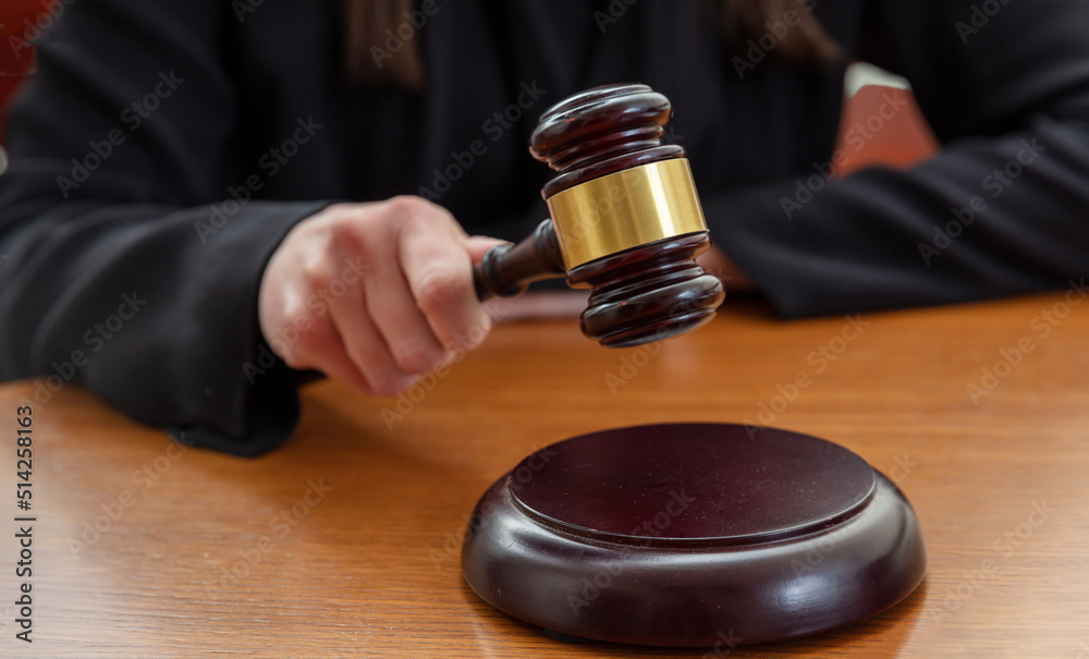 Judge female hand hold a gavel on law court bench, close up. Justice and punishment concept Judge female hand hold a gavel on law court bench, close up. Justice and punishment concept