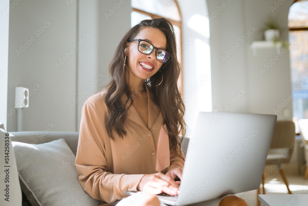 Young woman with wireless headphones calling on laptop, talk by webcam, video conference sitting on modern cafe. Freelancer working on a laptop. Business, online, education concept. Young woman with wireless headphones calling on laptop, talk by webcam, video conference sitting on modern cafe. Freelancer working on a laptop. Business, online, education concept.