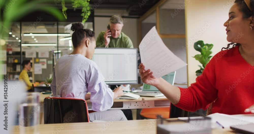 Happy diverse business people discussing work and holding documents at office Happy diverse business people discussing work and holding documents at office