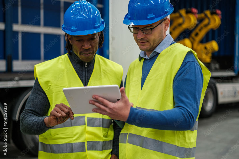 Fototapeta premium Two machine engineers reviewing the operation of the factory on their tablet