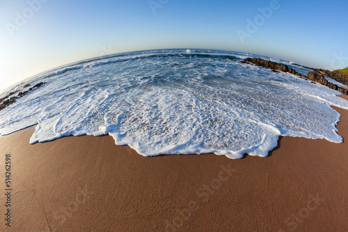 Fototapeta Naklejka Na Ścianę i Meble -  Beach sand ocean sea wave wash close up wide angle photo in morning light of nature's coastline detail.