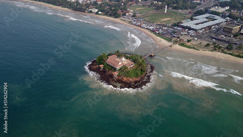 Small island off the coast of Sri Lanka seen from above. Located in the souther part of Sri Lanka, with a temple on the island, connected by a suspended bridge from the mainland photo