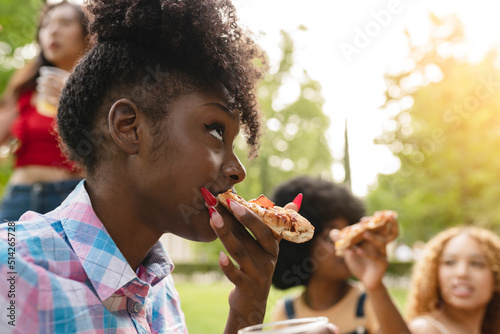 friends eat pizza in the park  focus african woman eating