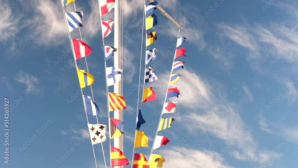 Sea ship flags on a mast waving in the wind against sunny blue sky ...