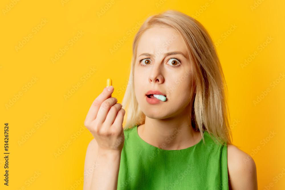 Stylish girl in green dress with pills on yellow background Stylish girl in green dress with pills on yellow background