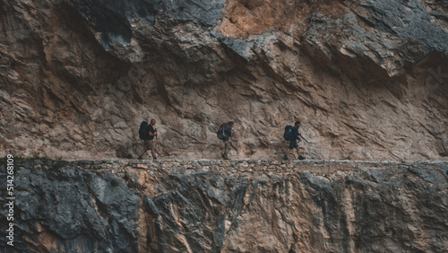 Three hikers in a rocky walking cave in the same direction and with the same separation between them. 