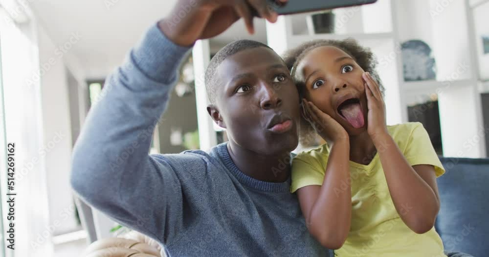Vertical video of african american father and daughter using smartphone