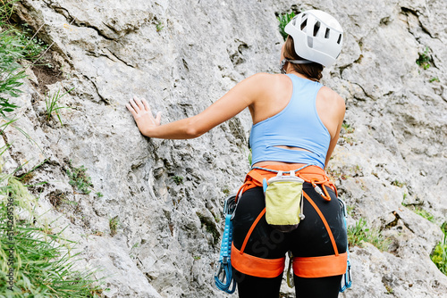 Unrecognizable female climber ascending on cliff in summer photo
