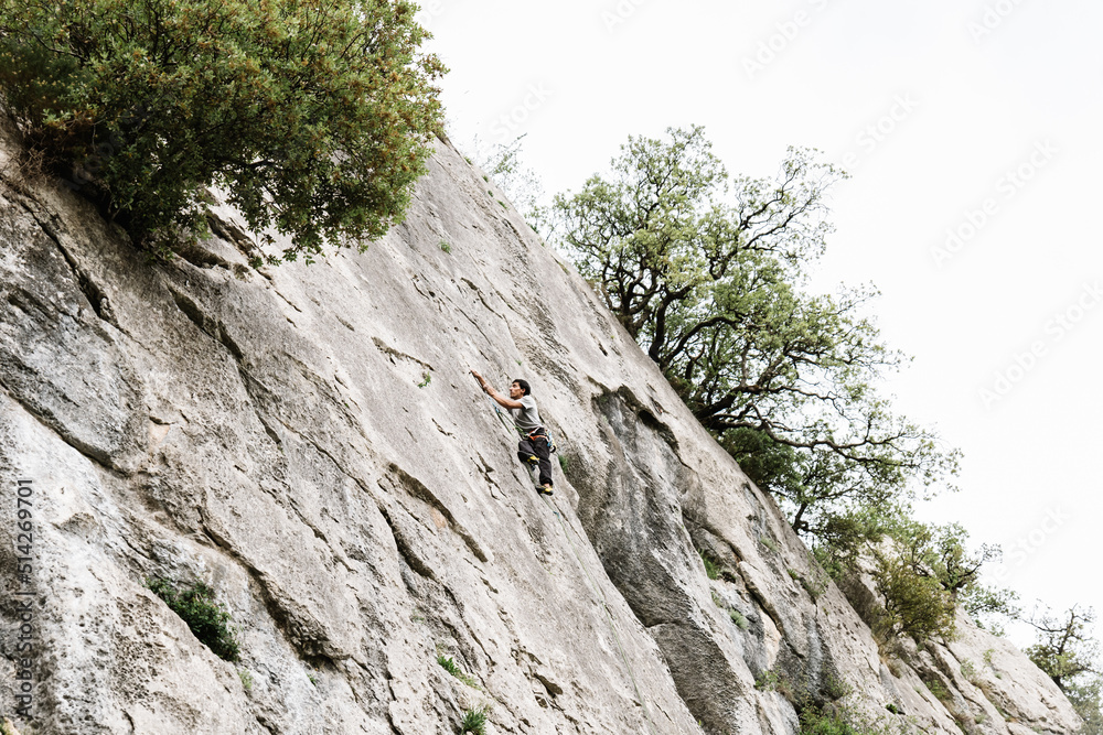 Male climber ascending on cliff in summer Male climber ascending on cliff in summer
