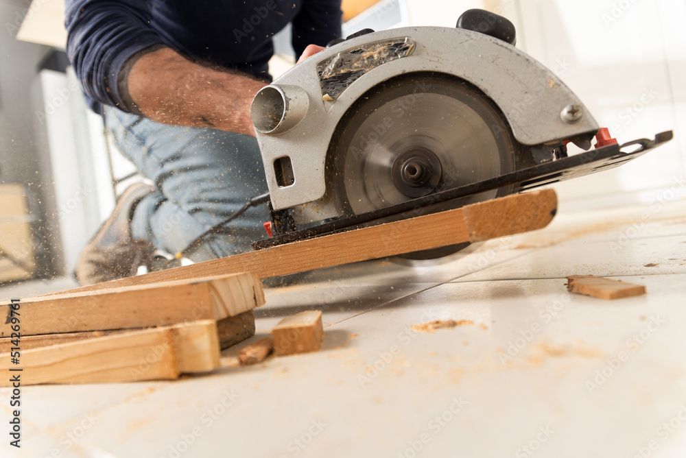 male carpenter working, cuts wood with a cutting machine, kneeling on the floor.
male carpenter working, cuts wood with a cutting machine, kneeling on the floor.