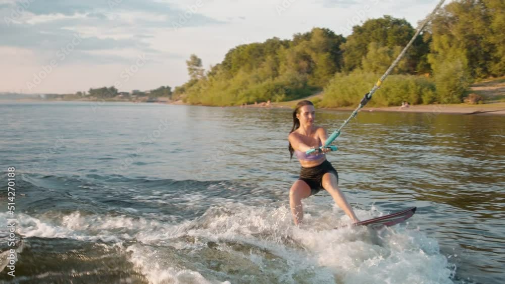 A female surfer jumping on a wakeboard. An experienced wakeboarder splashes water drops into the camera. A female surfer jumping on a wakeboard. An experienced wakeboarder splashes water drops into the camera.