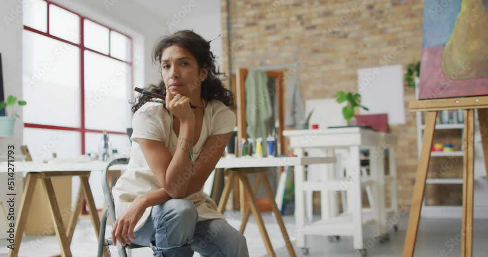 Video of happy biracial female artist smiling at camera in studio Video of happy biracial female artist smiling at camera in studio