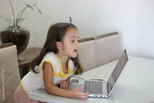 Criança brincando de jogo em frente do computador com pinturas ilustrativa.
 photo