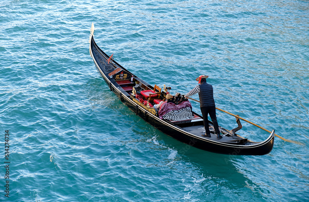 Venetian gondolier carries tourists on gondola in Grand Canal in Venice, Italy