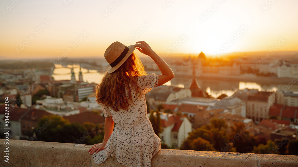 Young female tourist enjoys the view of the city at sunset. back view.  Lifestyle, travel, tourism, nature, active life.