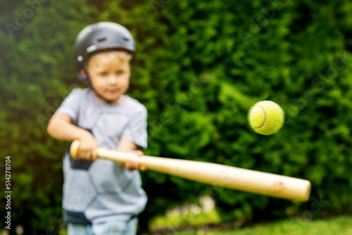 Canvas Print little boy hitting tennis ball with baseball bat at home backyard