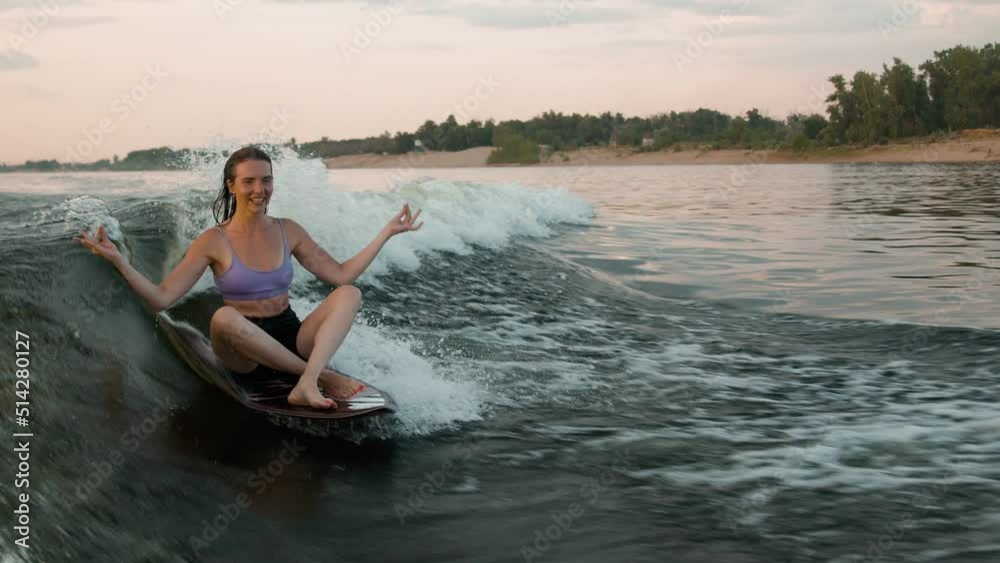 A female surfer jumping on a wakeboard. An experienced wakeboarder splashes water drops into the camera. A female surfer jumping on a wakeboard. An experienced wakeboarder splashes water drops into the camera.