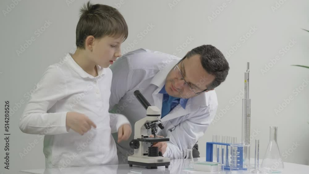 Young teacher explain to the student how to use laboratory microscope Young teacher explain to the student how to use laboratory microscope