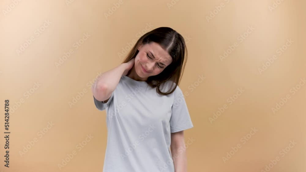 Woman with muscle injury having pain in her neck - body pain portrait shot on a beige background Woman with muscle injury having pain in her neck - body pain portrait shot on a beige background