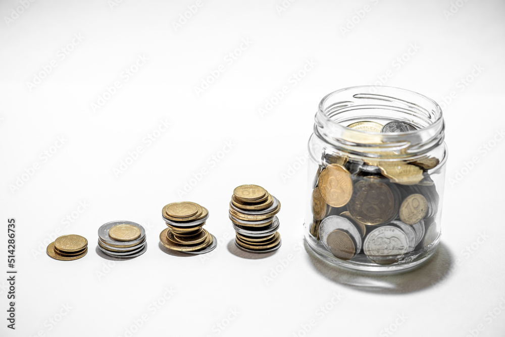 Clear glass jar for tips with coins money isolated on white. Finance concept Clear glass jar for tips with coins money isolated on white. Finance concept