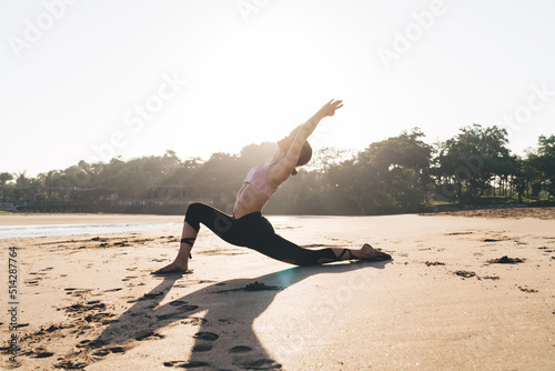 Flexible Caucasian woman in tracksuit training near seashore practicing yoga and meditation care about body health, athletic female breathing and feeling harmony mindfulness in asana at coastline