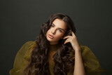 Fashion and hair care concept. Pretty young brunette woman with long wavy hairstyle and makeup on black background