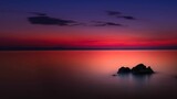 Widok skał oblewanych przez morze o wschodzie słońca przy kolorowym niebie