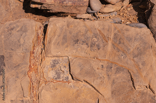 Stone textured background of sand color with real spots and cracks. Stone wall is sand-colored with real spots and deep uneven cracks.