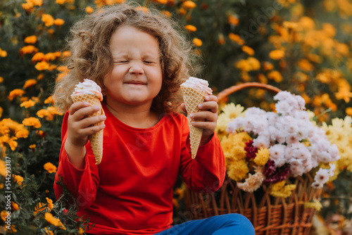 cute curly little girl eating ice cream in park fall time  autumn  card  flowers  banner