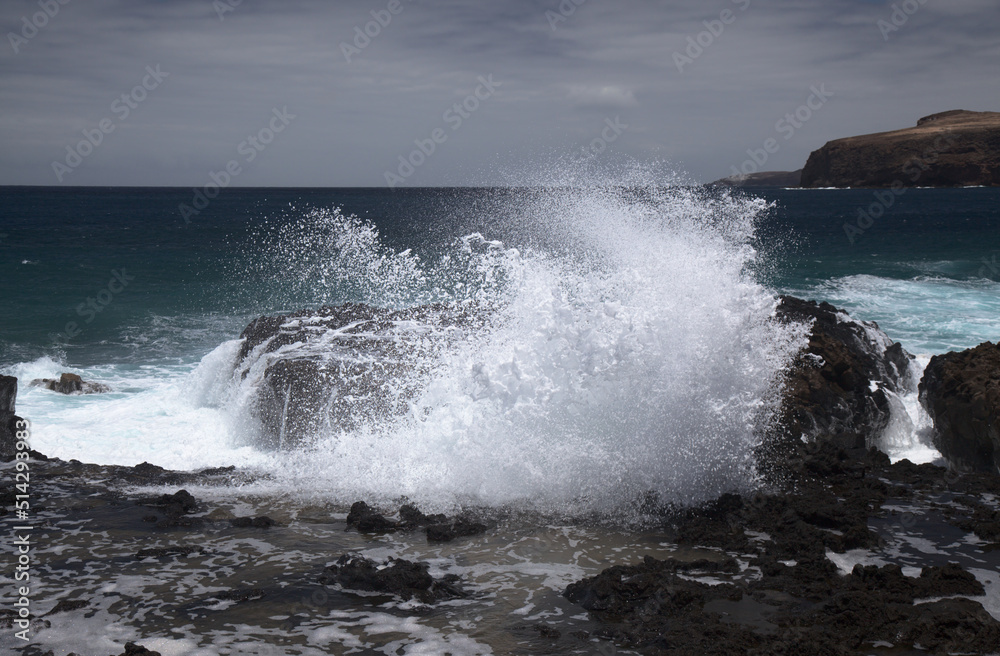 Gran Canaria, north west coast around natural swimming pools Salinas de Agaete, 
waves breaking against old eroded dark lava platform