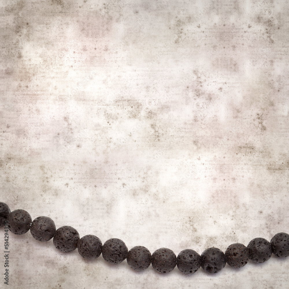 square stylish old textured paper background with necklace made of black volcanic lava beads
