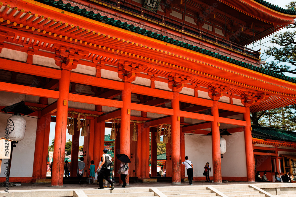 the entrance of a large Japanese temple with red columns and people walking inside the entrance of a large Japanese temple with red columns and people walking inside