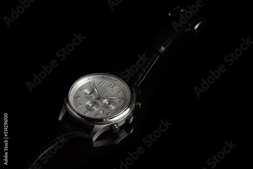 Studio shot of a silver fancy luxury unbranded Men watch on the black background. Stainless steel man's wrist watch with blue leather strap.