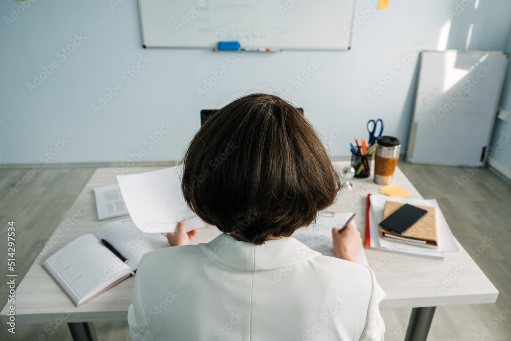 Young Businesswoman, manager sitting at table in office and do notes in diary and calendar Young Businesswoman, manager sitting at table in office and do notes in diary and calendar