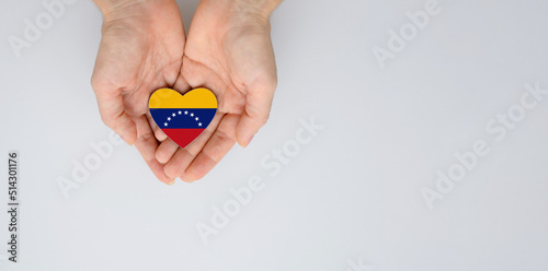 The national flag of Venezuela of arms in female hands. Flat lay, copy space.