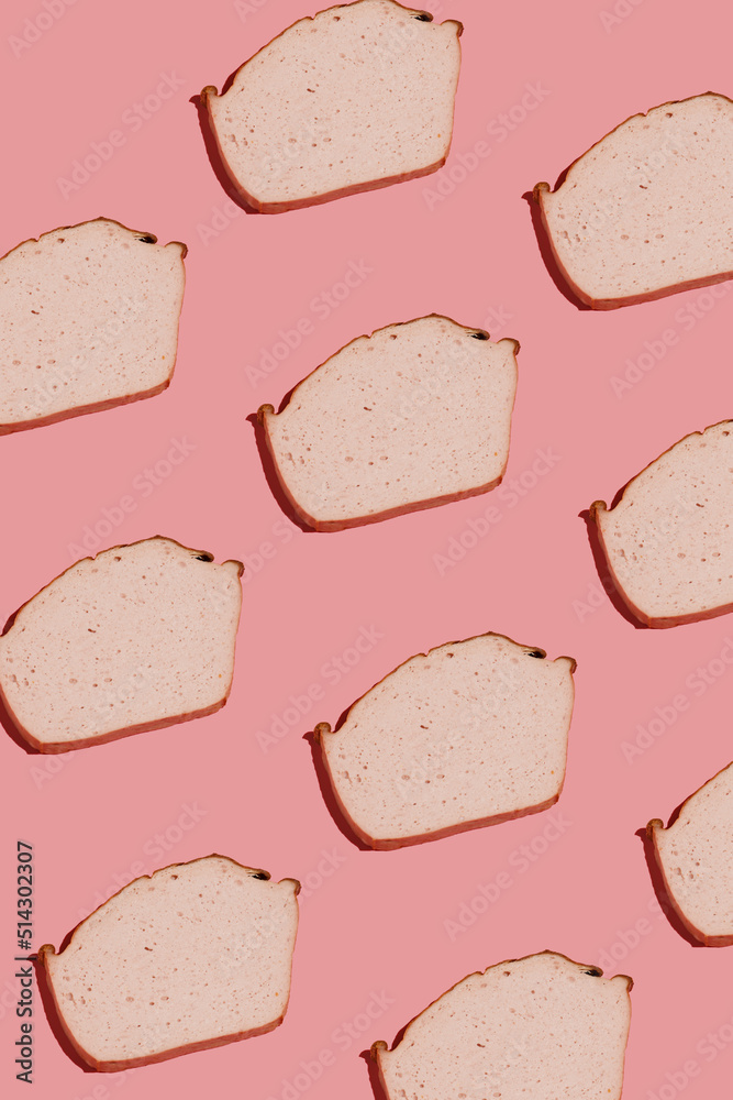 hard light pattern of a slice of traditional oven baked bavarian meal leberkäse - meat dish made of corned beef, pork and bacon, finely ground and baked as a bread loaf, pink background hard light pattern of a slice of traditional oven baked bavarian meal leberkäse - meat dish made of corned beef, pork and bacon, finely ground and baked as a bread loaf, pink background