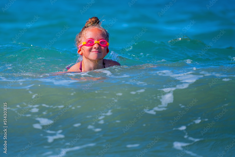 Portrait of happy child girl on breaking wave. Copy space for text or design.