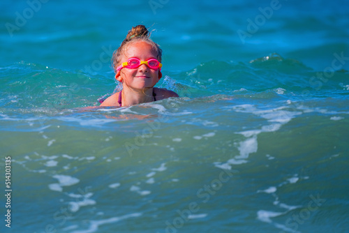 Portrait of happy child girl on breaking wave. Copy space for text or design.
