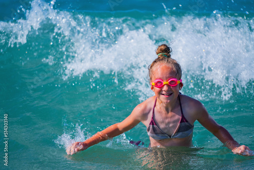 Funny portrait of happy child girl on breaking wave. Copy space.
