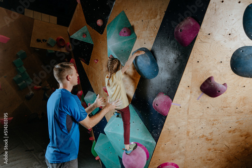 Rock climber father and daughter climbing in a modern gym