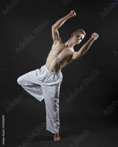 red-haired male dancer demonstrates the choreographic elements of the dance. photo shoot in the studio on a dark background