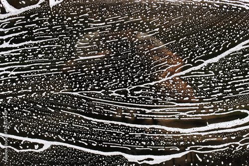 Valokuva Background, texture of the black surface of a metal door, car windows in white soapy foam after washing