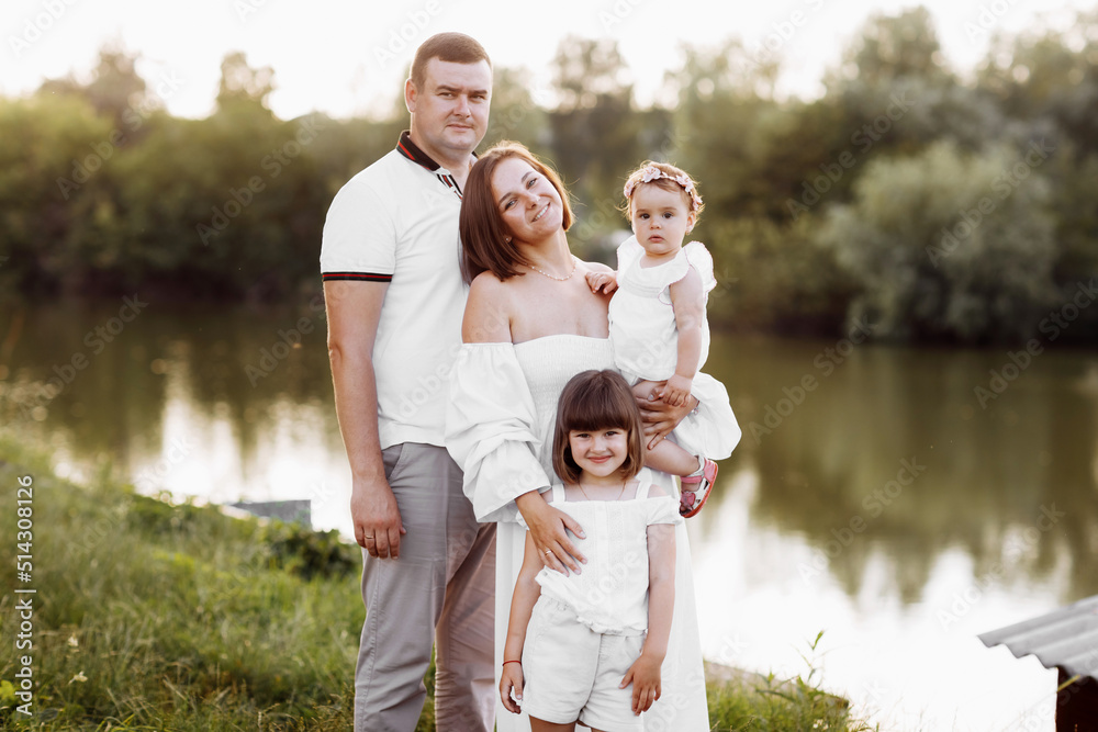 young dad and mom with child daughter and baby girl having fun by the pond or lake on summer day. happy family concept. mother's, father's, baby's day. young dad and mom with child daughter and baby girl having fun by the pond or lake on summer day. happy family concept. mother's, father's, baby's day.