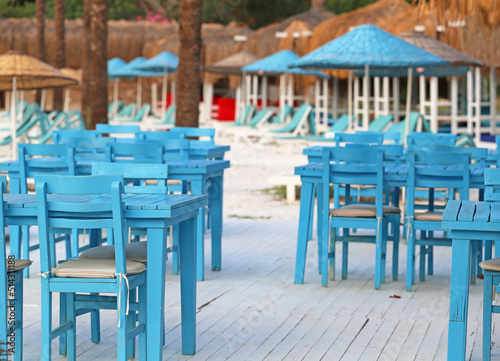 Obraz na płótnie Blue tables and chairs sun loungers and beach umbrellas w salonie