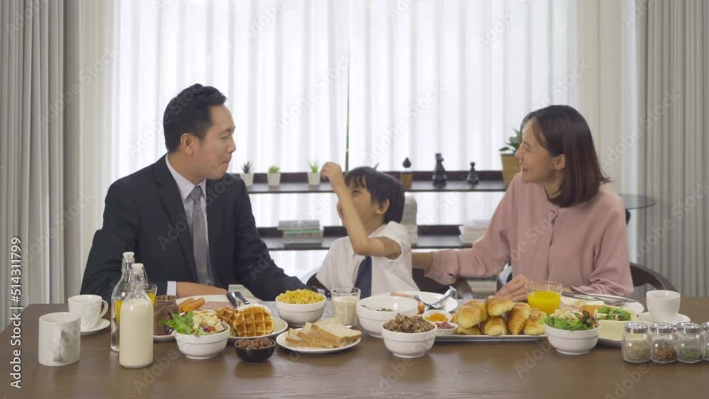 Portrait of happy smiling Asian Family eating breakfast food together before the child going to school at home. Family relationship. Love of father, mother, and son. People lifestyle. Business man. Portrait of happy smiling Asian Family eating breakfast food together before the child going to school at home. Family relationship. Love of father, mother, and son. People lifestyle. Business man.