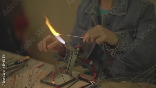 close-up video shot of woman making handmade glass beads with fire