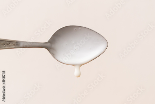 Fresh yogurt on a spoon isolated on white. Delicious yogurt drips from the spoon. Liquid drops. Image for dairy product packaging design.