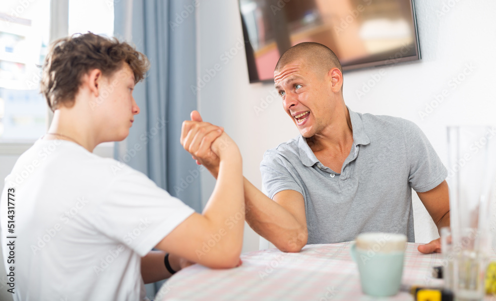 Obraz premium Father arm wrestling his son. They're happy and havung fun.