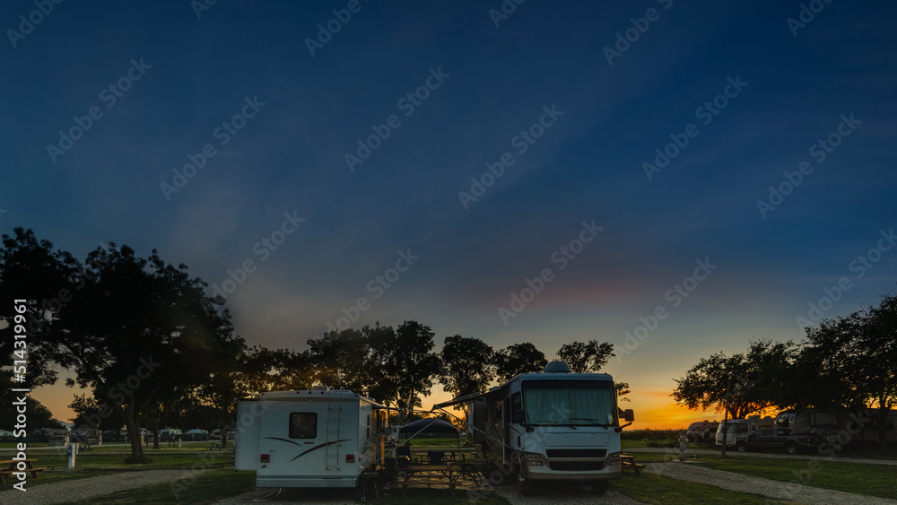 Camping under colorful sunset sky in camper Rv parked door to door for companionship 
