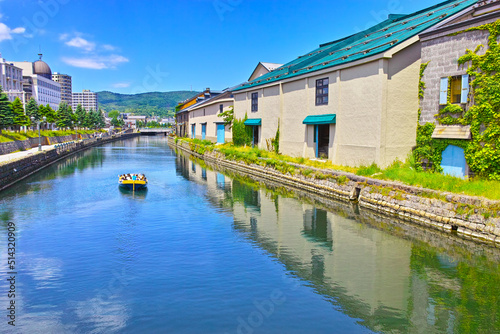 新緑の北海道小樽市、浅草橋街園から見る快晴の小樽運河の倉庫群と運河クルーズ船